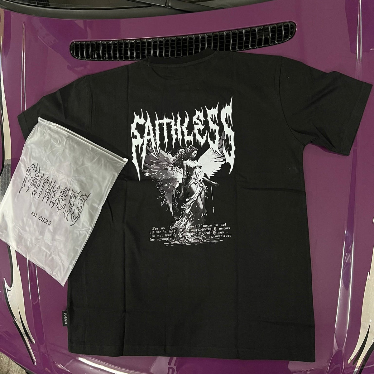 Black Angel tee, back view with large Faithless lettering and angel print, on a purple car hood