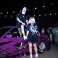 Black Angel tee worn at a night meet, back print with angel and Faithless lettering, next to a purple BMW