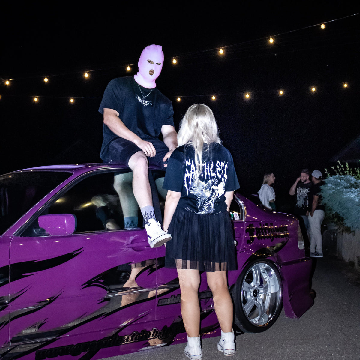 Black Angel tee worn at a night meet, back print with angel and Faithless lettering, next to a purple BMW