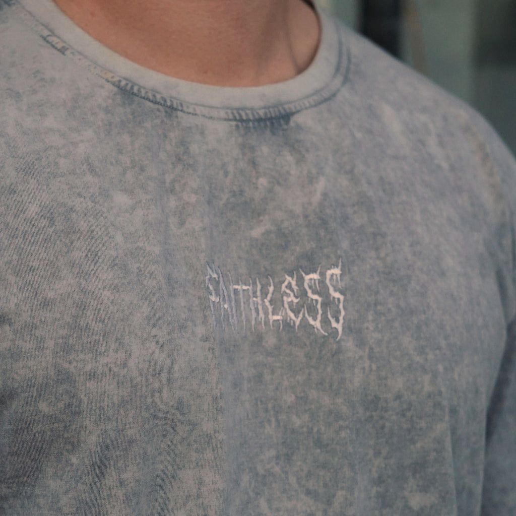 Flare tee in washed grey worn, close-up of the white Faithless chest embroidery